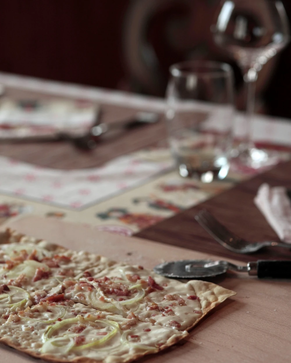 Tarte flambée aux lardons et aux oignons, servie sur planchette